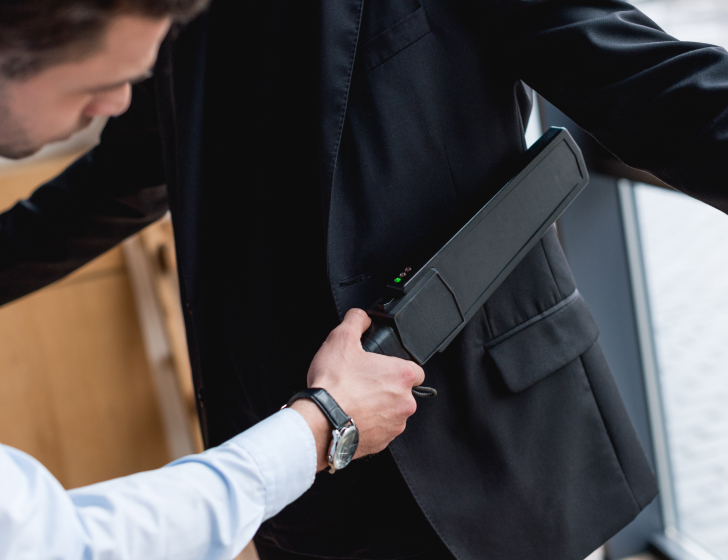 Cropped View of Guard Using Metal Detector